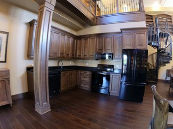 Creekside common room a kitchen with wooden cabinets and a spiral staircase in the background